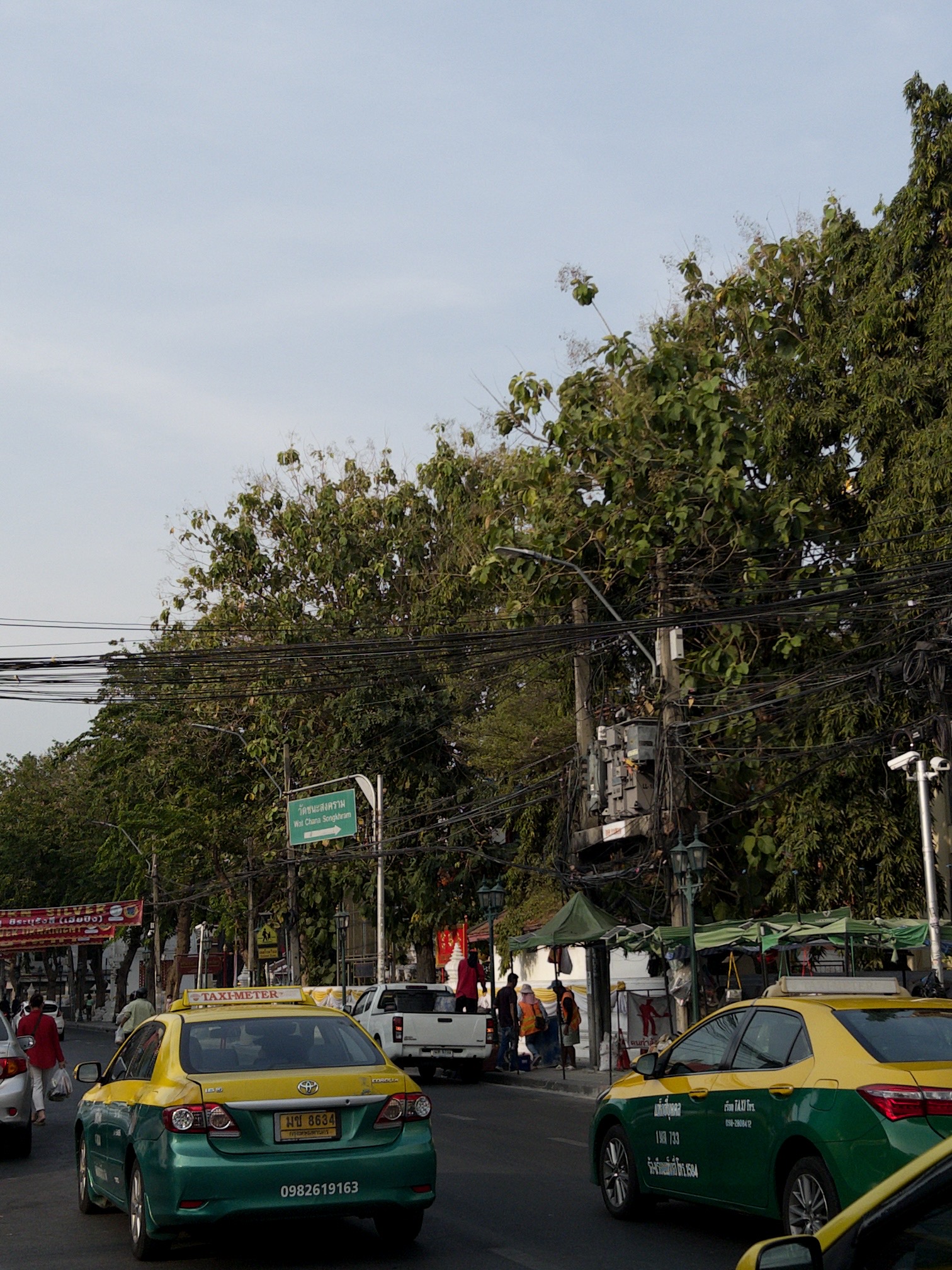 Motorbike taxi on a narrow, wire-strung street in Thailand at dusk